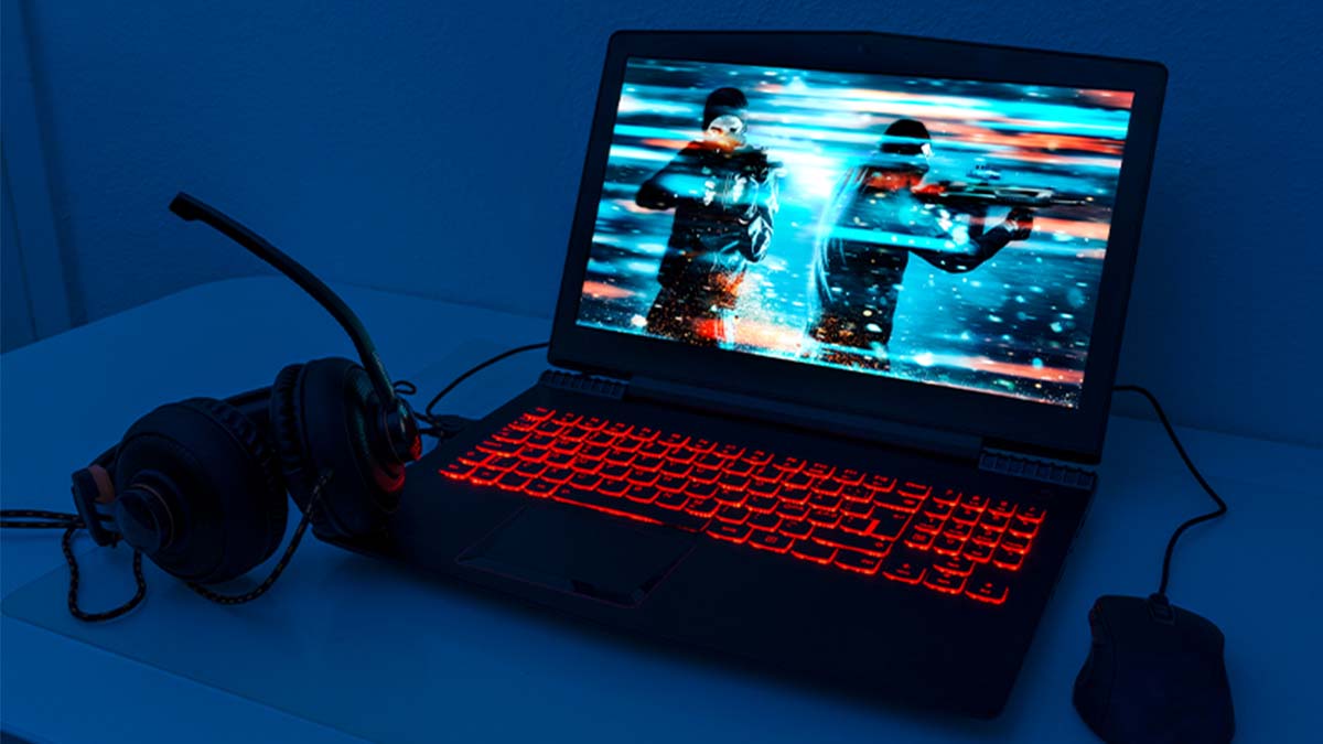 Portátil com mouse e phones para jogos em cima de uma mesa com fundo azul escuro e ecrã a mostrar um jogo de guerra